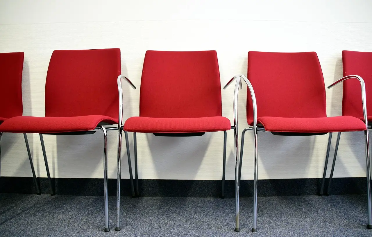 A row of empty chairs in a bright waiting room